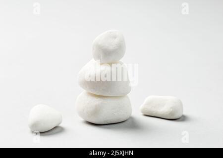 Stacked White zen rocks balance on the grey background. Balancing pebble stones Stock Photo
