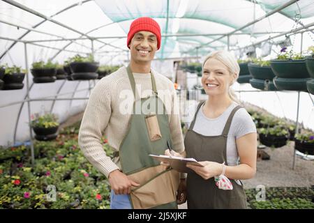 Portrait happy plant nursery owners working in greenhouse Stock Photo