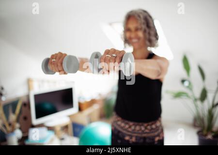 Senior woman exercising with dumbbells at home Stock Photo