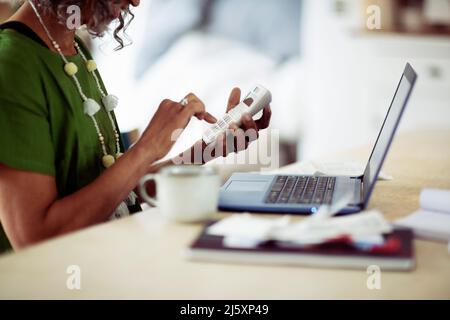Senior woman using calculator at laptop Stock Photo