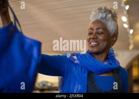 Happy senior woman in blue shopping Stock Photo