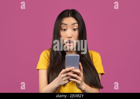 Portrait of surprised korean lady looking at smartphone screen with excitement, emotionally reacting to mobile offer Stock Photo