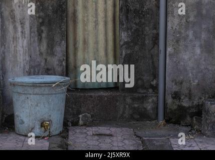 Grungy scene of blue trash can and dirty black and gray background in Bali, Indonesia Stock Photo