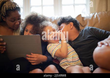 Mother and children with digital tablet on sofa Stock Photo