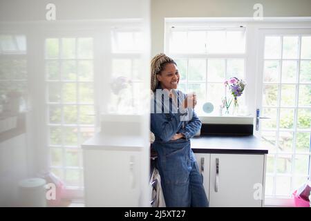 Happy woman drinking coffee in kitchen Stock Photo