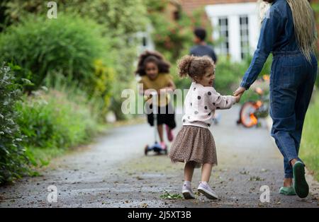 Happy daughter holding hands with mother on driveway Stock Photo