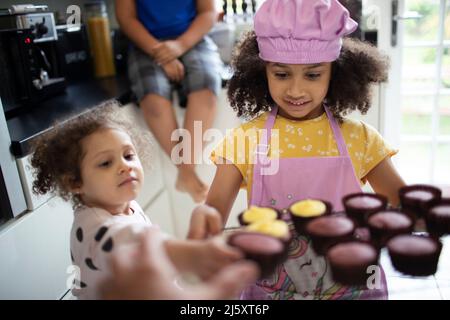 Cute girls baking cupcakes in kitchen Stock Photo