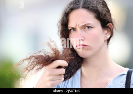 Angry woman with curly hair complaining about split ends in the street Stock Photo