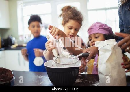 Family baking sifting flour in kitchen Stock Photo