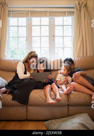 Mother and kids using digital tablet on living room sofa Stock Photo