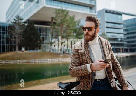 Man using smartphone. Standing next to bicycle with smartphone and looking away. Copyspace Stock Photo