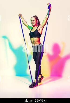Strong girl working with resistance band. Photo of model with