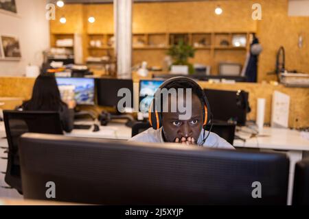 Focused businessman in headset working at computer in office Stock Photo
