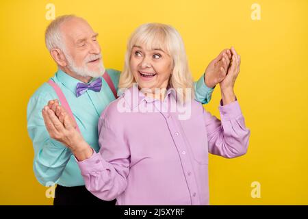 Portrait of two attractive cheerful grey-haired spouses dancing surprise party isolated over bright yellow color background Stock Photo