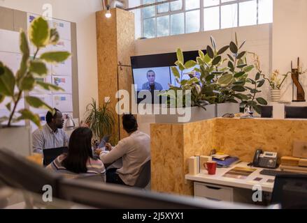 Building designers video chatting with colleagues on screen in office Stock Photo