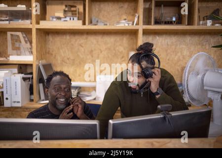 Businessmen with headphones working at computers in office Stock Photo