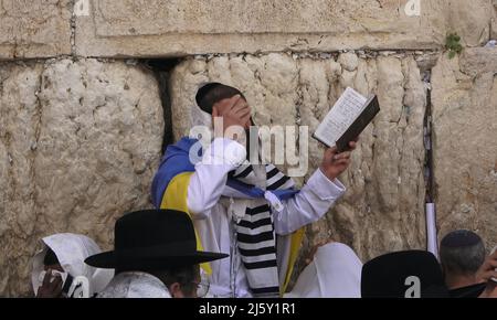 A Jewish worshiper wrapped with the Ukrainian flag and Talit prayer shawl prays as religious Jews of the Cohanim Priestly caste take part in the bi-annual mass 'Birkat Kohanim' or 'Priestly Blessing' on the holiday of Pesach (Passover) at the Kotel in Jerusalem, Israel. Stock Photo