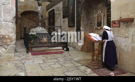 A Russian Orthodox nun prays at the basement where remnants of the emperor Constantine’s original 4th-century Holy Sepulchre church can be seen inside the Church of Saint Alexander Nevsky in the Old City on April 20, 2022 in Jerusalem, Israel. Russian President Vladimir Putin demanded recently that Israel hand over the church and its compound known as 'Alexander courtyard' to Russian sovereignty according to an agreement by the previous Israeli administration. Stock Photo