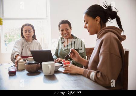 Happy mother and daughters eating breakfast at home Stock Photo