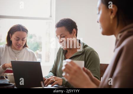 Happy woman working from home in dining room with daughters Stock Photo