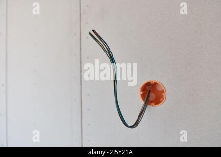 Power cables hang out on the wall in preparation for electrical installation during house construction Stock Photo