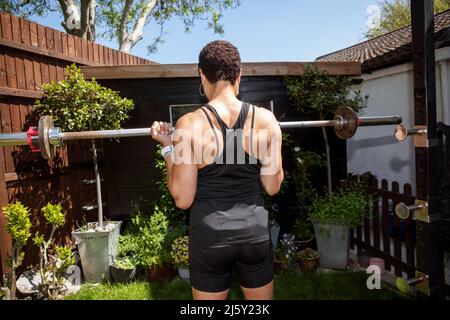 Strong woman weight training in sunny backyard Stock Photo