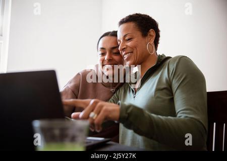 Happy mother and young adult daughter using laptop Stock Photo