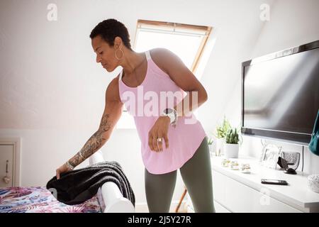 Mature woman with tattoos getting dressed in bedroom Stock Photo