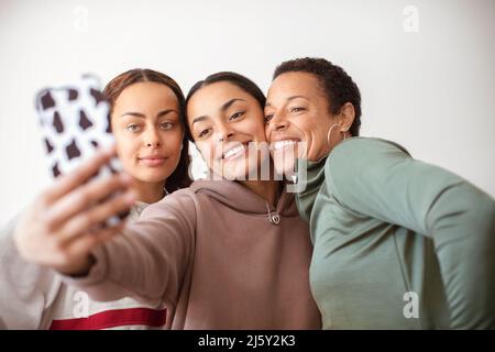 Happy mother and young adult daughters taking selfie with smart phone Stock Photo