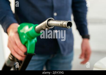 Cropped unrecognizable man refilling vehicle tank at petrol station during energy crisis Stock Photo