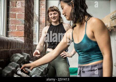 Women friends working out with dumbbells in gym Stock Photo