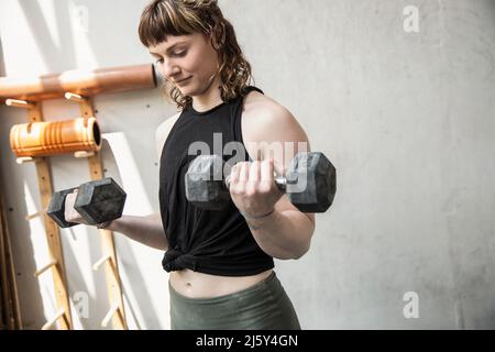 Young woman weightlifting with dumbbells in gym Stock Photo