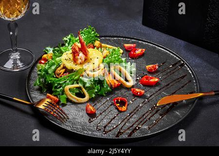 Asian style salad of greens with fried squid, shrimps, mussels and pineapple Stock Photo