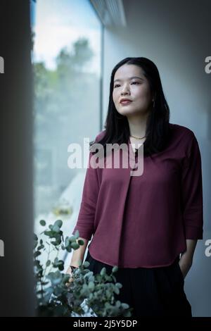 Thoughtful young woman looking out window Stock Photo