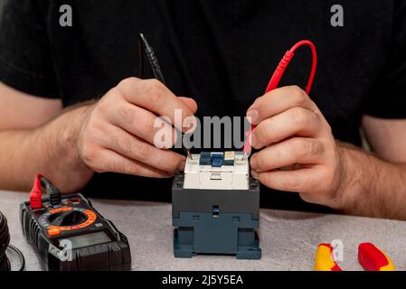 Electrician checking the proper functioning of the switch box with a digital multimeter Stock Photo