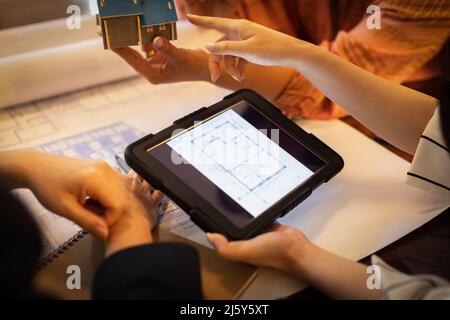 Close up architects with digital tablet discussing blueprints Stock Photo