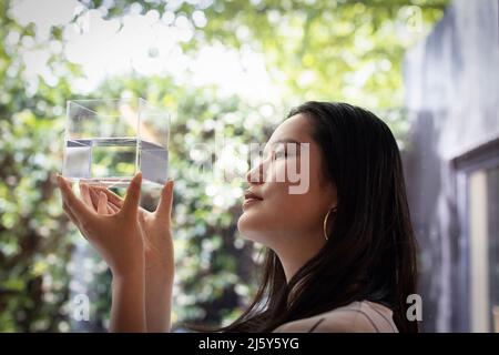 Creative female designer looking at cube with water at window Stock Photo