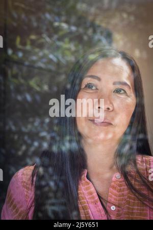 Close up thoughtful woman looking out window Stock Photo