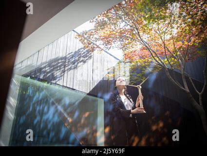 Female engineer with wind turbine model standing in courtyard Stock Photo