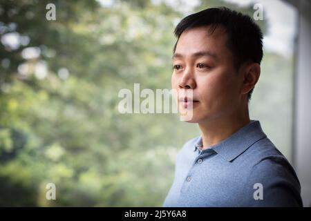 Curious man looking out window Stock Photo