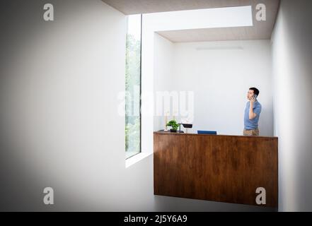 Male engineer talking on smart phone behind desk in office Stock Photo