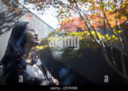 Thoughtful young woman looking up in courtyard Stock Photo