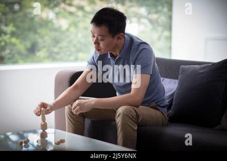 Man stacking wood pieces at coffee table in living room Stock Photo