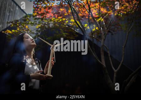 Hopeful female engineer with wind turbine model in courtyard Stock Photo