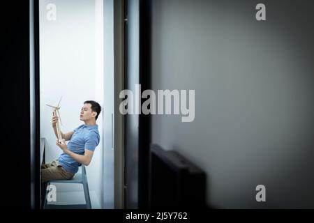 Male architect looking at wind turbine model in office doorway Stock Photo