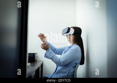 Businesswoman using VR headset in office Stock Photo