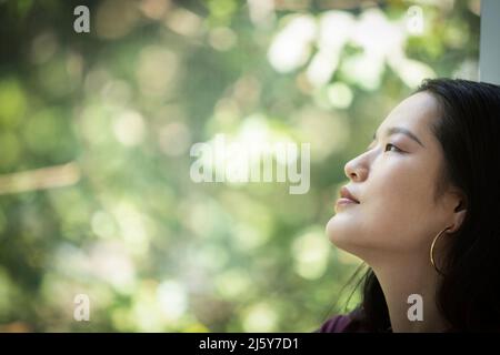 Profile serene young woman looking out window Stock Photo
