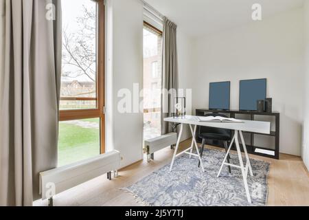 White table with opened book placed on rug near windows in light spacious home office with decorative frames in flat Stock Photo