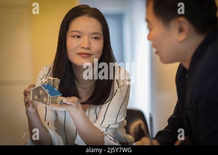 Architects discussing tiny house model in office meeting Stock Photo