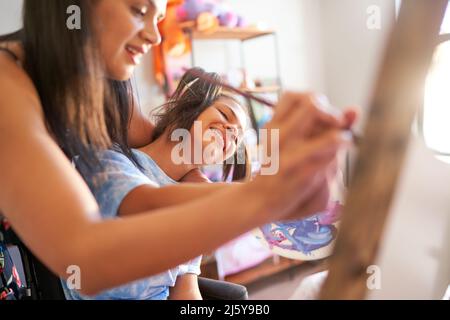 Happy mother and disabled daughter painting together at home Stock Photo